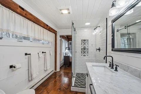a bathroom with a sink a toilet a mirror and shower