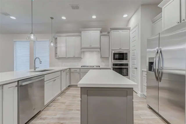 a kitchen with kitchen island a counter top stainless steel appliances and cabinets