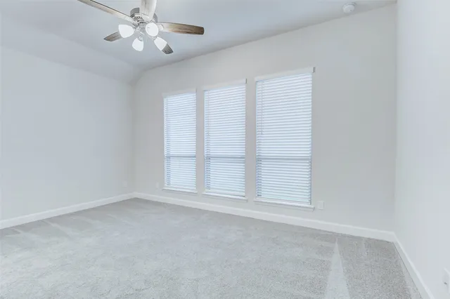 an empty room with windows and chandelier fan