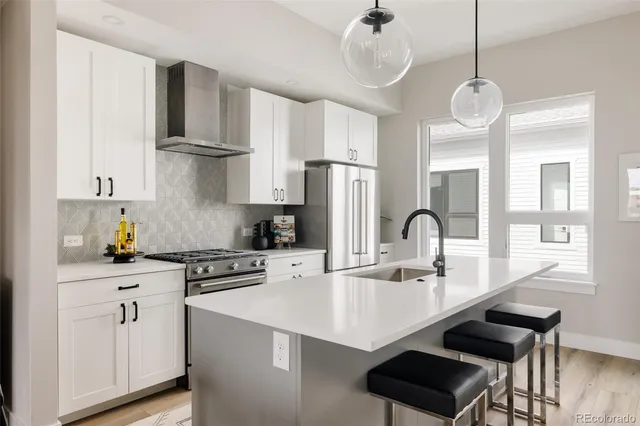 a kitchen with stainless steel appliances a sink a stove a refrigerator and cabinets