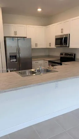 a kitchen with stainless steel appliances granite countertop a refrigerator a stove and a sink with wooden floor