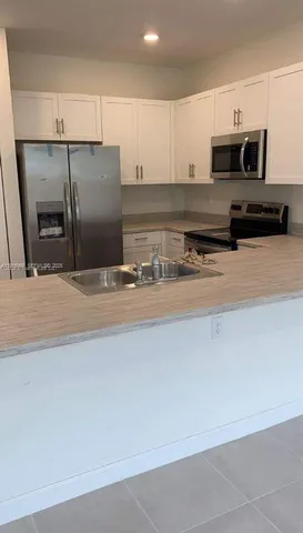 a kitchen with stainless steel appliances granite countertop a refrigerator a stove and a sink with wooden floor