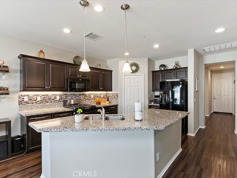 1580 Williamson Park Beaumont, CA 92223 - Photo 7 of 48 a kitchen with stainless steel appliances kitchen island granite countertop a sink a stove and a wooden floors