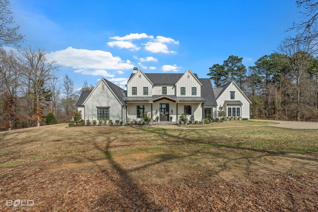 5296 Linton Cutoff Road Benton, LA 71006 - Photo 1 of 40 Modern farmhouse with covered porch, a front lawn, board and batten siding, a standing seam roof, and a chimney