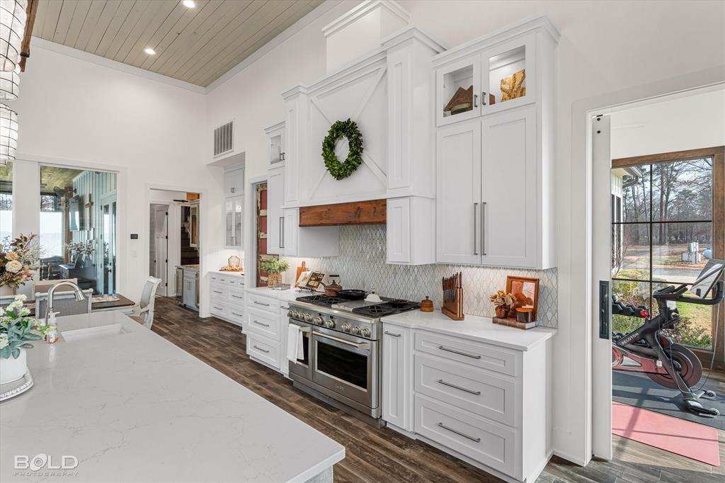 5296 Linton Cutoff Road Benton, LA 71006 - Photo 21 of 40 Kitchen with glass fronted cabinets, white cabinets, dark wood-style flooring, double oven range, and light stone counters