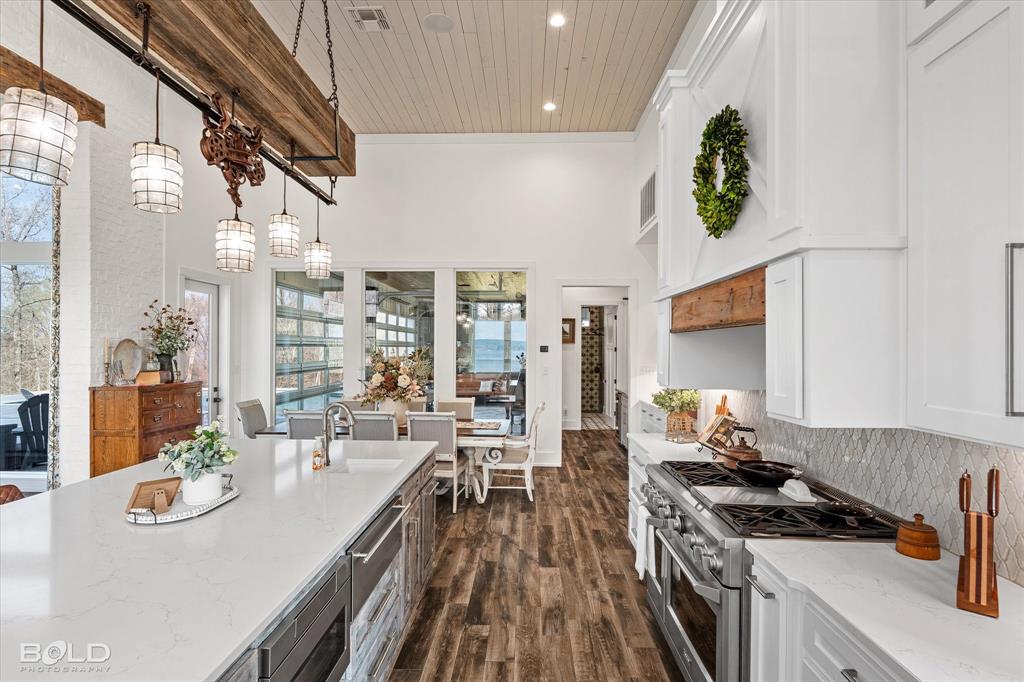 5296 Linton Cutoff Road Benton, LA 71006 - Photo 22 of 40 Kitchen featuring light stone countertops, stainless steel appliances, dark wood finished floors, white cabinets, and a high wooden ceiling