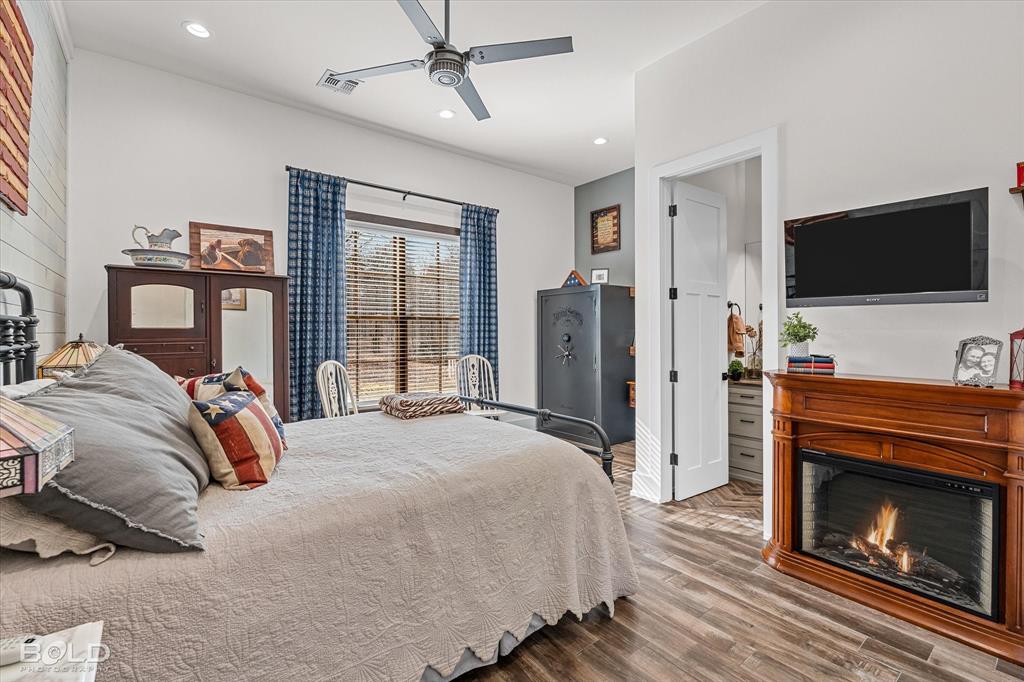 5296 Linton Cutoff Road Benton, LA 71006 - Photo 29 of 40 Bedroom featuring wood finished floors, a lit fireplace, recessed lighting, and a ceiling fan