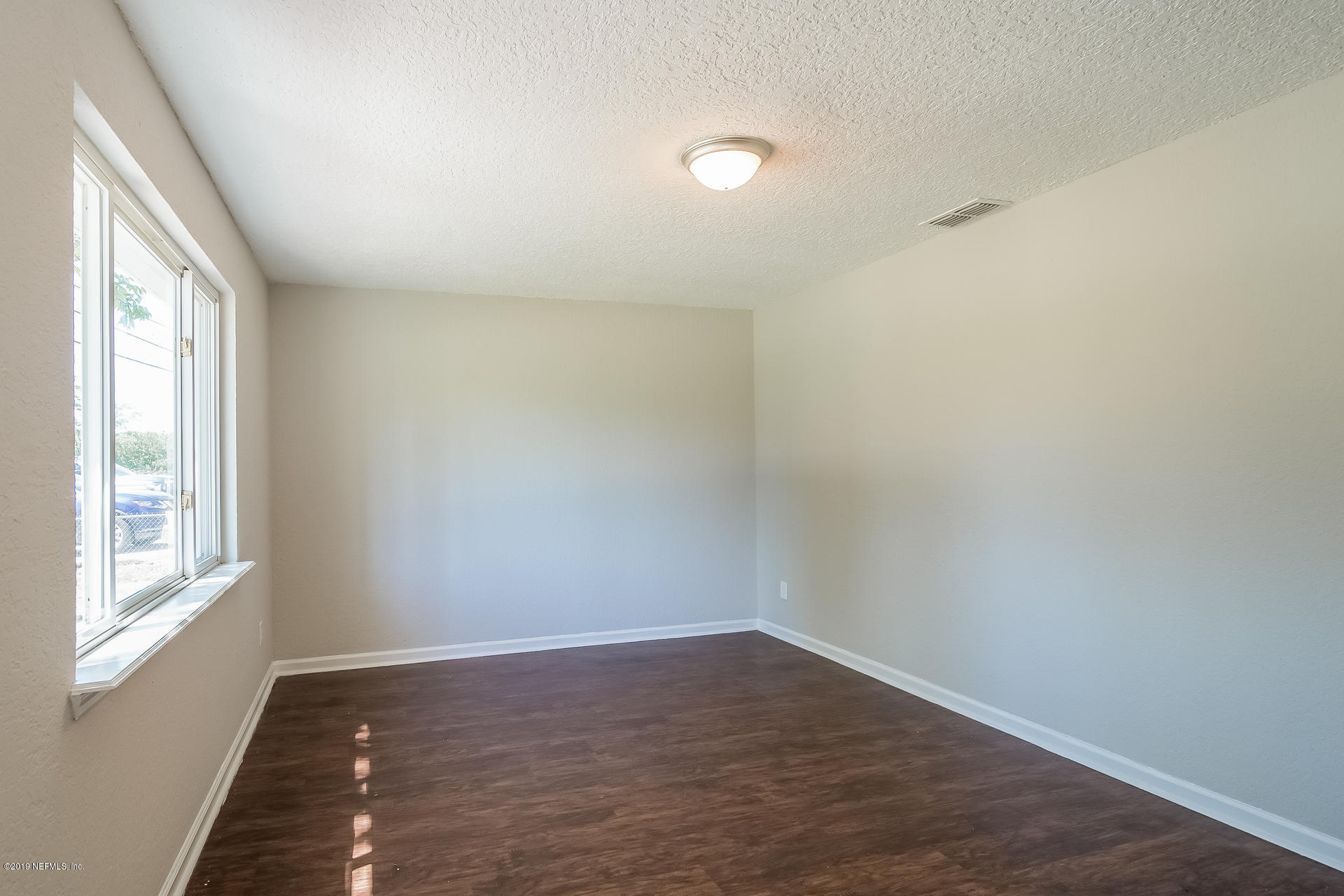 4527 Barnes Road South Jacksonville, FL 32207 - Photo 9 of 25 a view of an empty room with wooden floor and a window