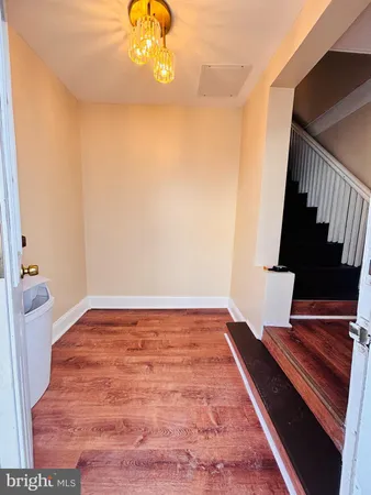 a view of an empty room with wooden floor and a potted plant