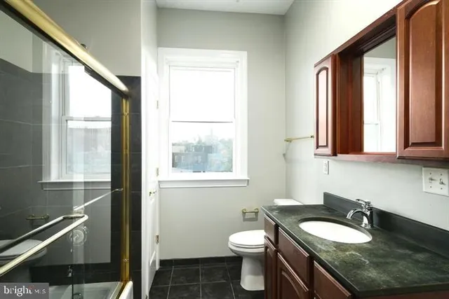 a bathroom with a granite countertop sink toilet a mirror and window