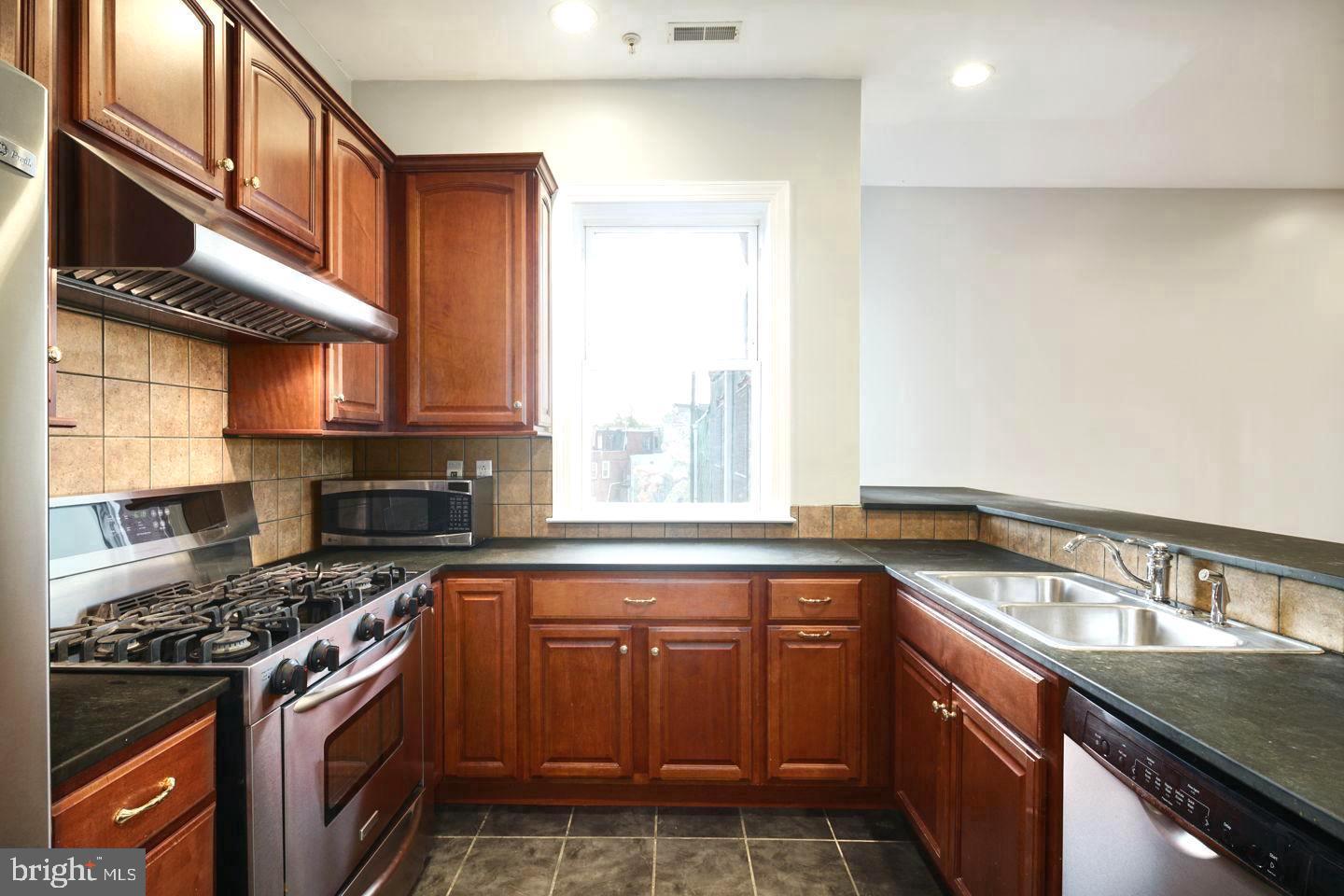 3933 Lancaster Avenue, Unit A Philadelphia, PA 19104 - Photo 7 of 22 a kitchen with stainless steel appliances granite countertop a stove a sink and a microwave