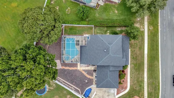 an aerial view of a house with swimming pool and large trees