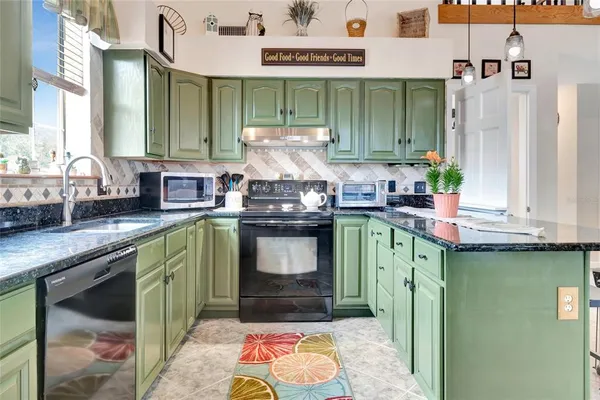 a kitchen with stainless steel appliances granite countertop a stove a sink and a microwave