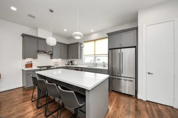 a kitchen with stainless steel appliances a dining table chairs stove a sink and dishwasher a refrigerator with wooden floor