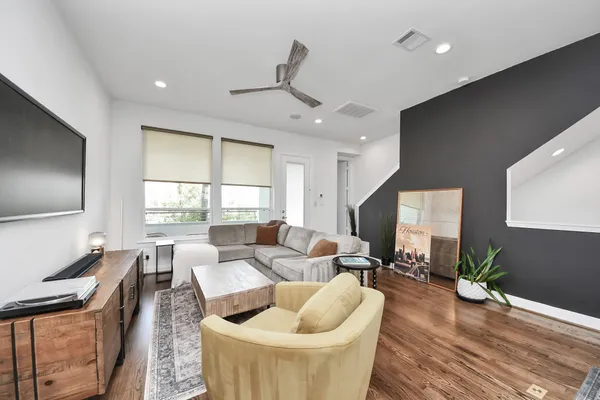 a living room with furniture a large window wooden floor and a rug