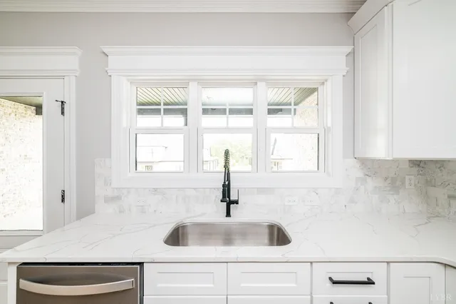 a kitchen with white cabinets sink and stove