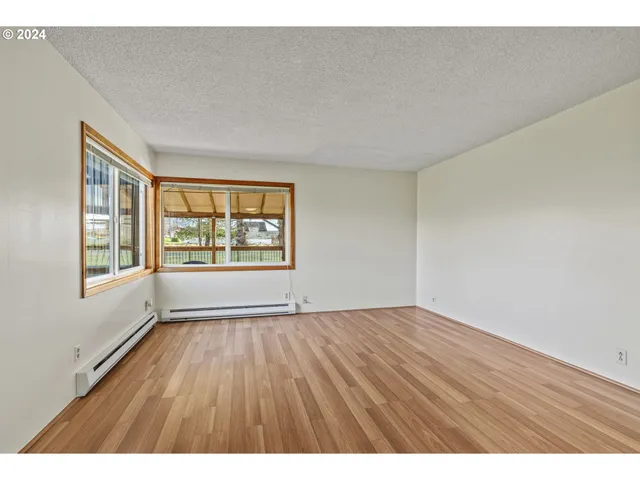 a view of an empty room with a window and wooden floor