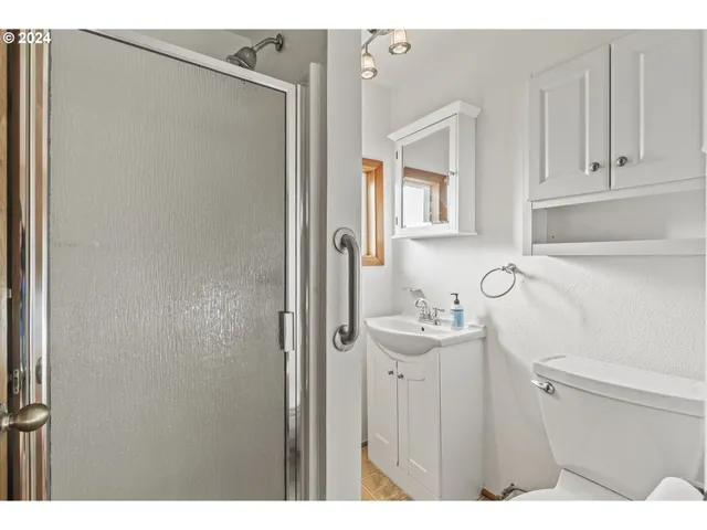 a bathroom with a sink a toilet and shower