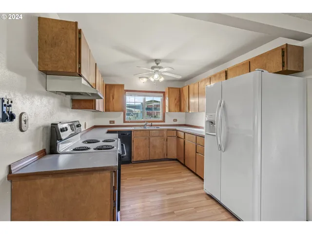 a kitchen with stainless steel appliances granite countertop a refrigerator a sink dishwasher a stove with wooden cabinets