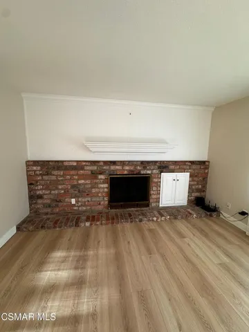 a view of an empty room with wooden floor and a fireplace