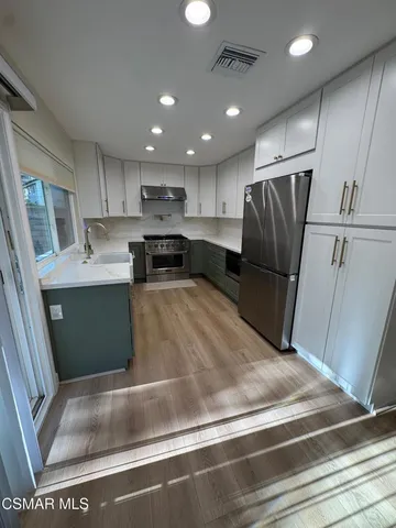 a view of a kitchen with refrigerator and white cabinets