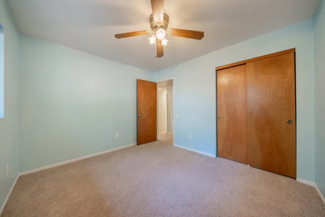 a view of an empty room with a chandelier fan