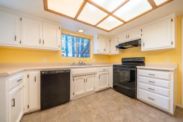 a kitchen with granite countertop a sink cabinets and stainless steel appliances
