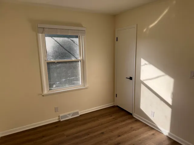 an empty room with wooden floor and a window