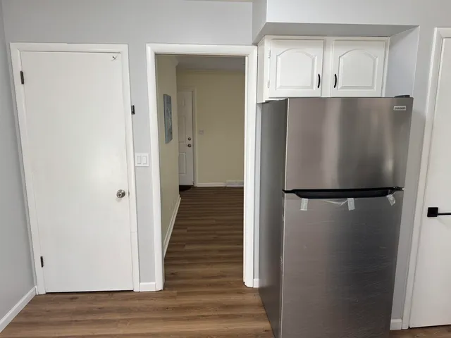 a view of an empty room with wooden floor and closet
