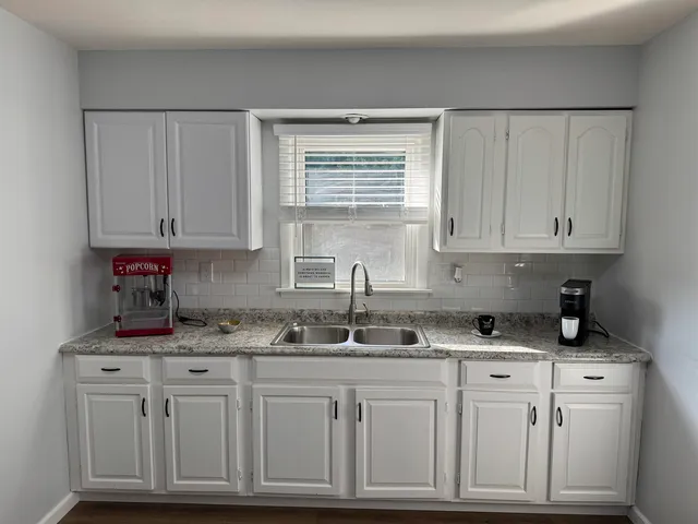 a kitchen with granite countertop white cabinets and sink