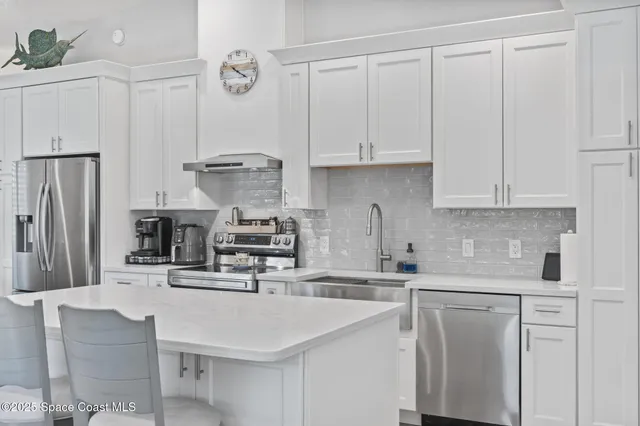 a large white kitchen with sink and washing machine