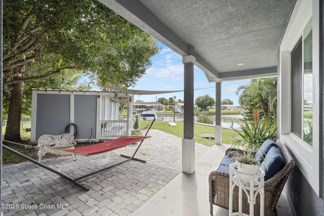 a patio with a table and chairs and potted plants