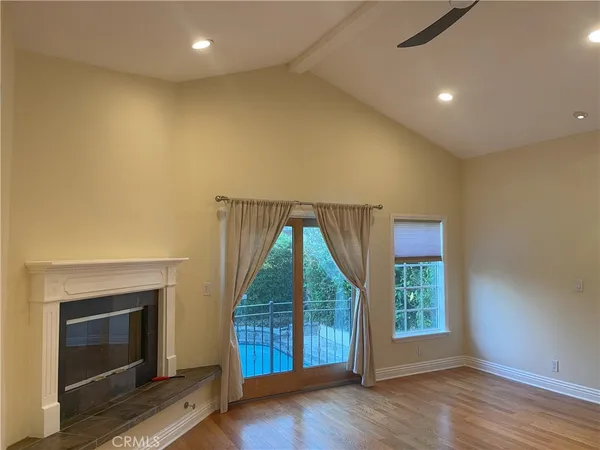 an empty room with wooden floor fireplace and windows