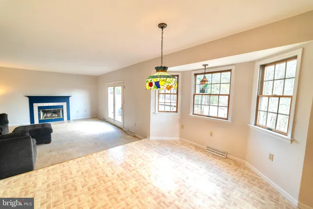 a view of an empty room with window and kitchen view