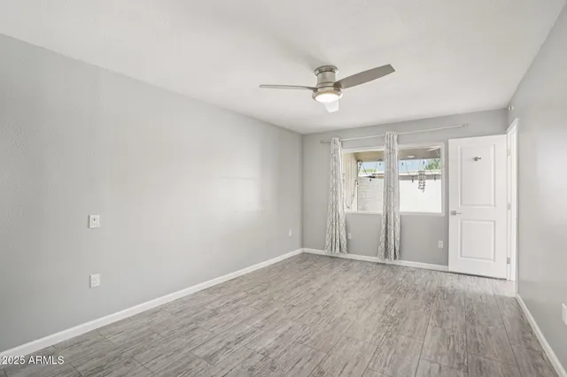 an empty room with wooden floor a ceiling fan