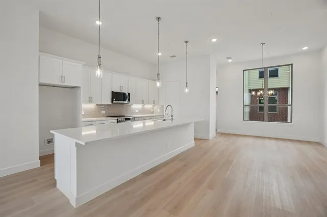 a kitchen with stainless steel appliances a stove a sink and white cabinets