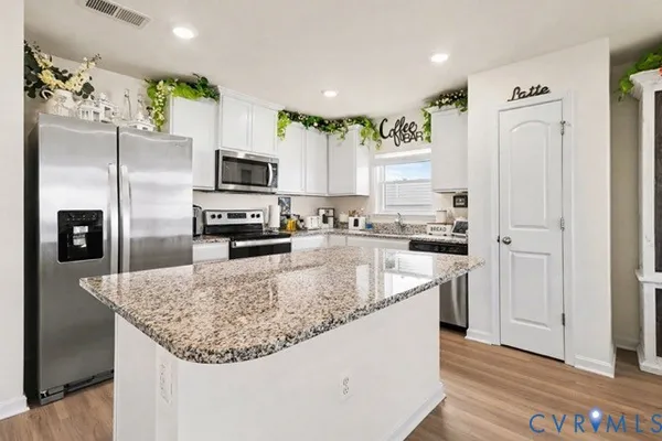 a kitchen with stainless steel appliances granite countertop a refrigerator a stove and a sink