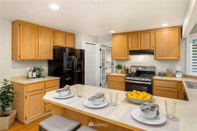 a kitchen with stainless steel appliances granite countertop a sink dishwasher a refrigerator a stove and a refrigerator with wooden floor