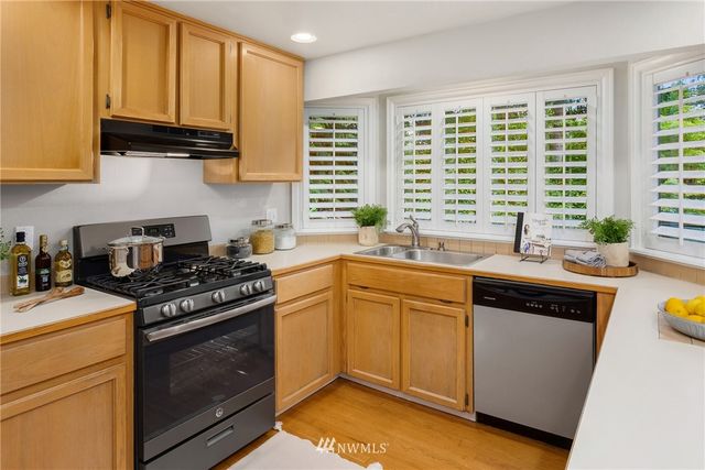 a kitchen with stainless steel appliances granite countertop a sink a stove and a refrigerator