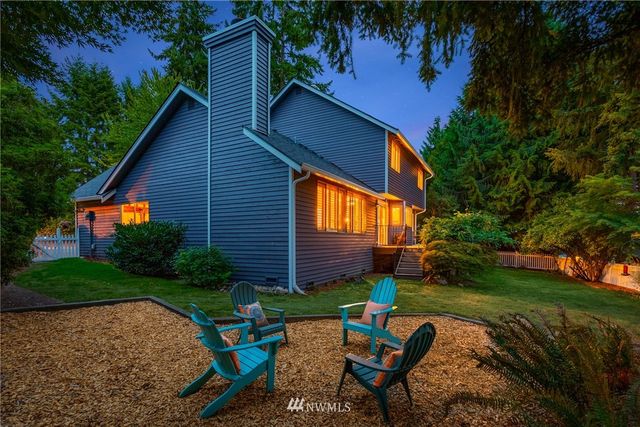 a backyard of a house with garden plants and outdoor seating
