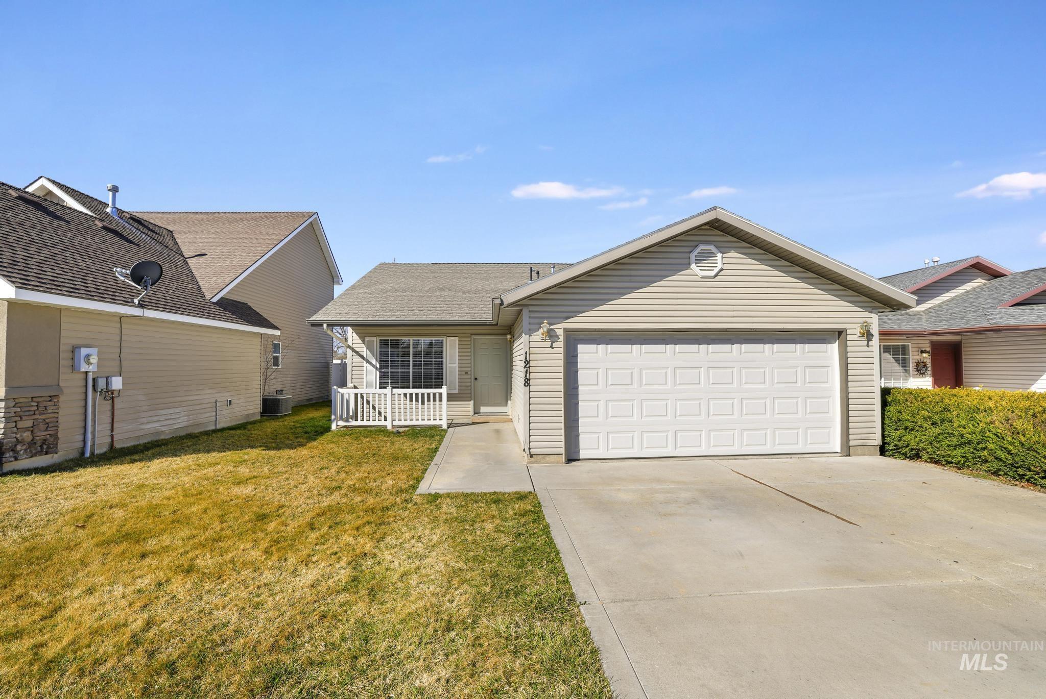Ranch-style home featuring driveway, a front yard, a garage, and roof with shingles