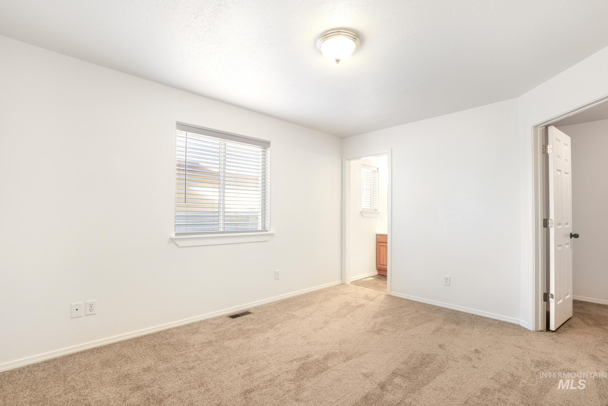 1218 Inca Drive Twin Falls, ID 83301 - Photo 14 of 27 Unfurnished bedroom with light carpet, ensuite bathroom, and a walk in closet