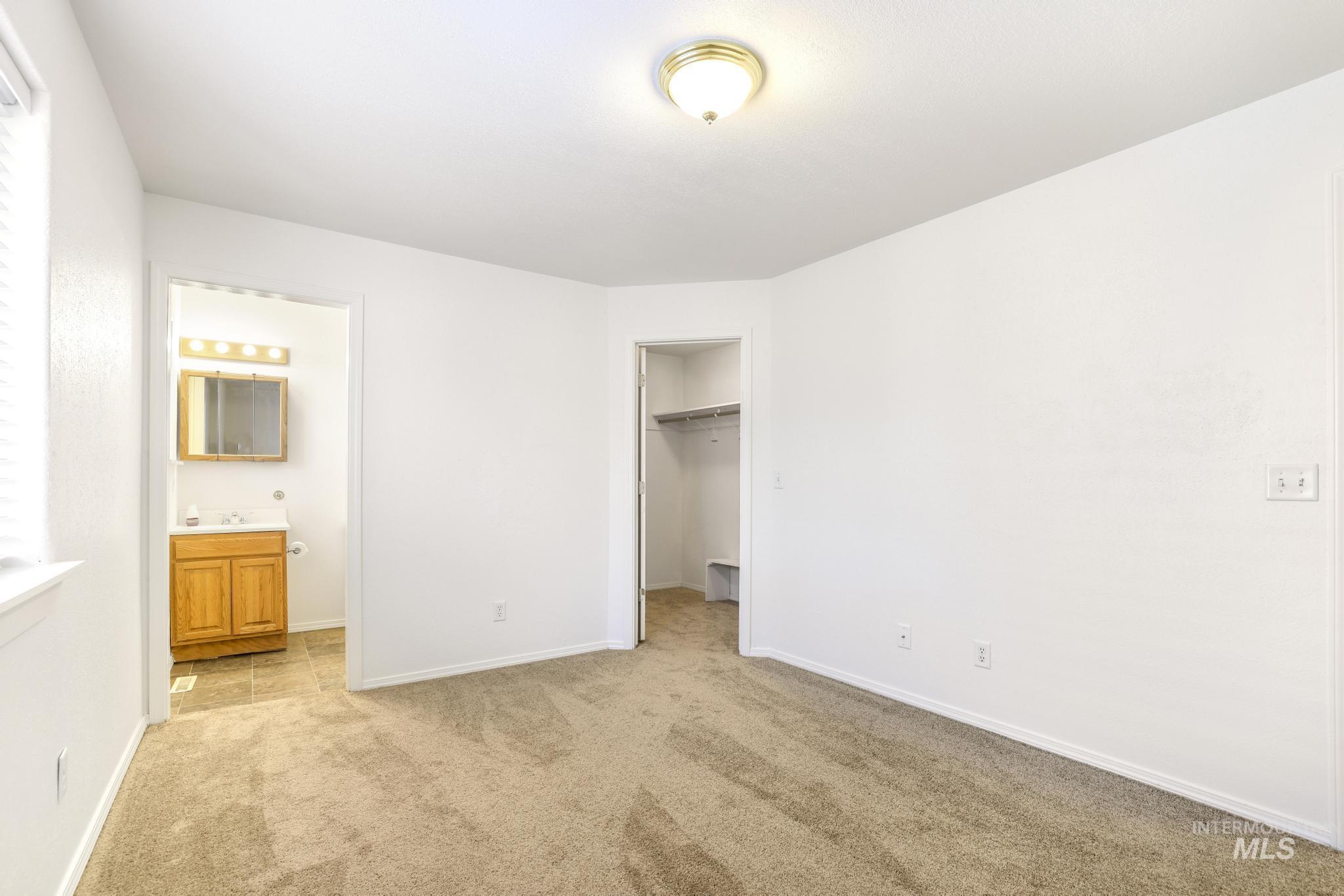 1218 Inca Drive Twin Falls, ID 83301 - Photo 15 of 27 Unfurnished bedroom with a walk in closet, light colored carpet, and ensuite bathroom