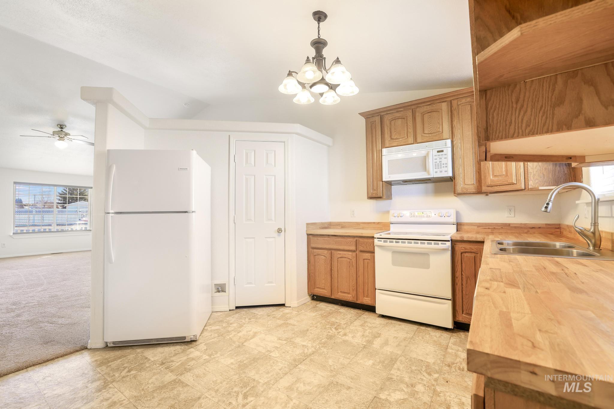 1218 Inca Drive Twin Falls, ID 83301 - Photo 7 of 27 Kitchen with white appliances, suspended lighting, vaulted ceiling, ceiling fan, and light colored carpet