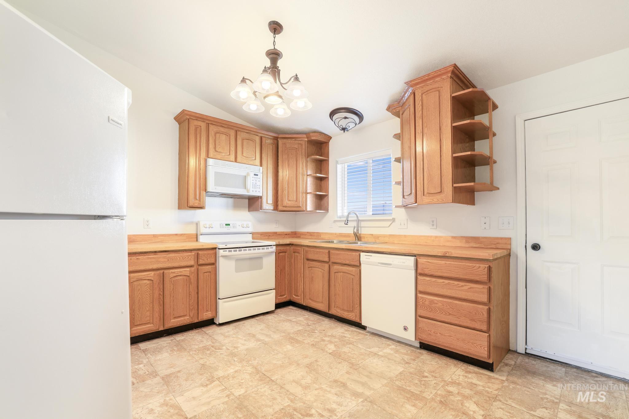 1218 Inca Drive Twin Falls, ID 83301 - Photo 8 of 27 Kitchen with white appliances, open shelves, vaulted ceiling, and a chandelier