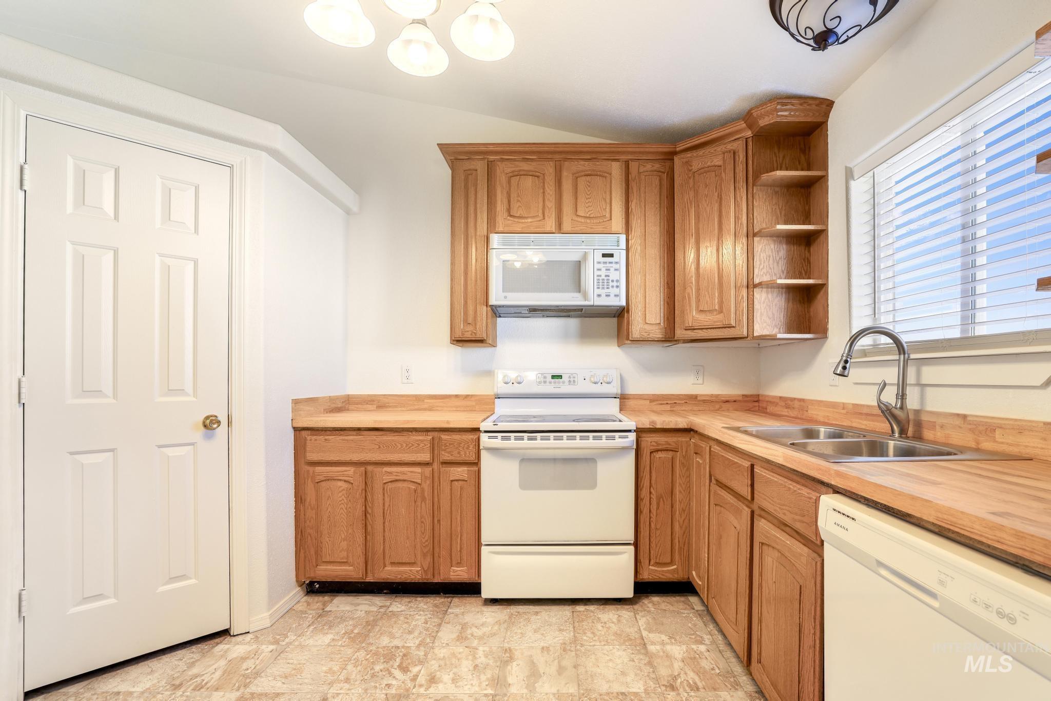 1218 Inca Drive Twin Falls, ID 83301 - Photo 10 of 27 Kitchen featuring white appliances, open shelves, wood finish cabinetry, stone finish flooring, and butcher block counters