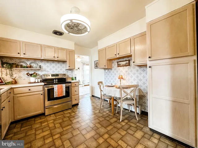 a kitchen with stainless steel appliances granite countertop a refrigerator a stove a sink a dining table and chairs with wooden floor