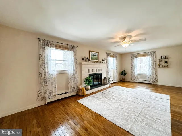 an empty room with windows fireplace and wooden floor