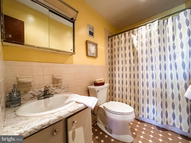 a bathroom with a granite countertop sink and a toilet