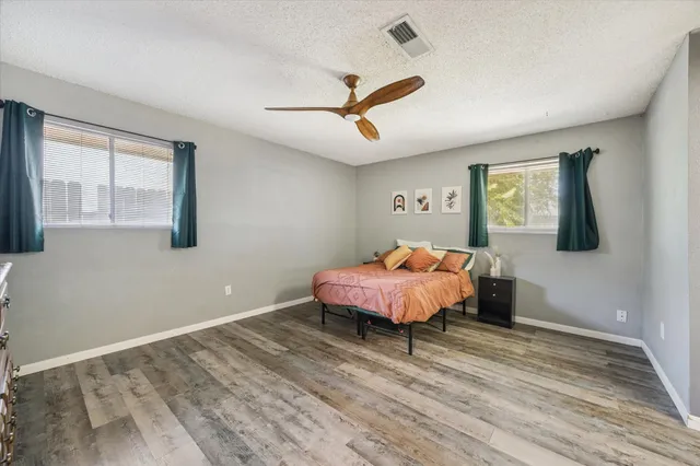 a spacious bedroom with a bed and wooden floor
